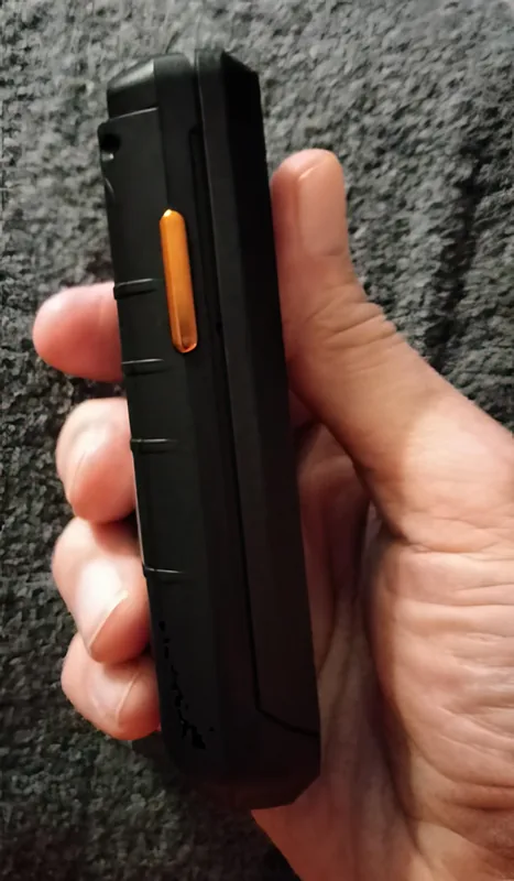In the hand, showing the side and the orange programmable key