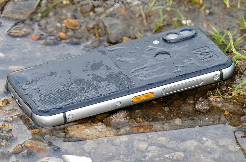 Lying in shallow running water, showing the side buttons and SIM tray