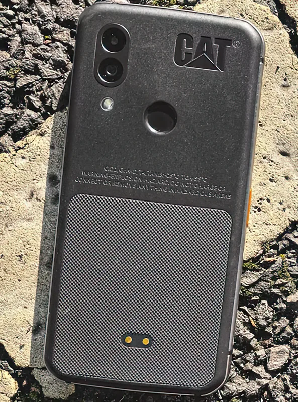 Lying on gravel, showing the pogo pins and the moulded warning text on the back
