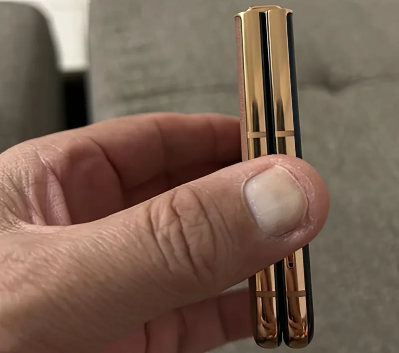 The folded phone seen edge-on between finger and thumb, showing how thin it closes